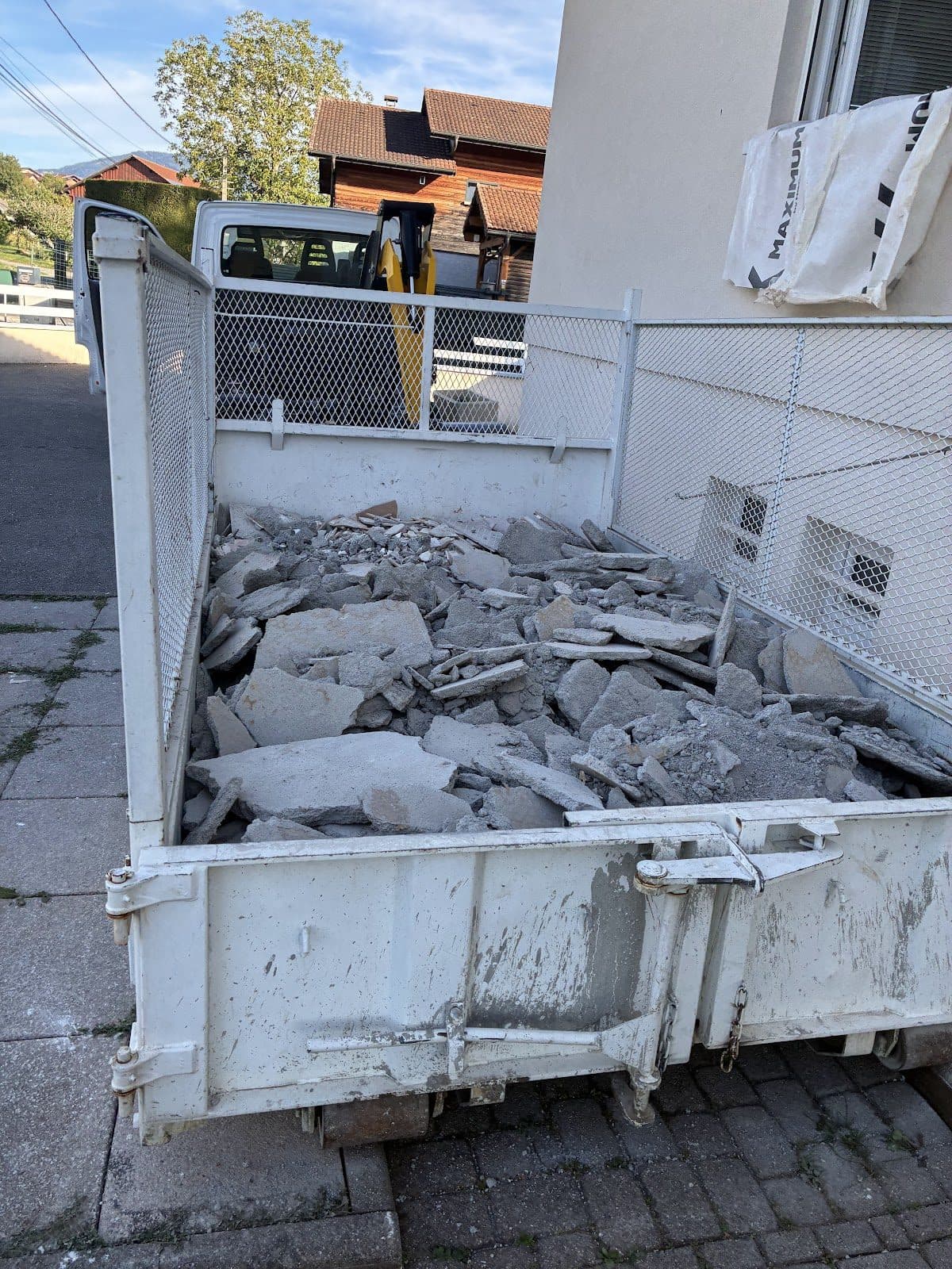 Benne de gravats déposée dans une cour à l'accès étroit